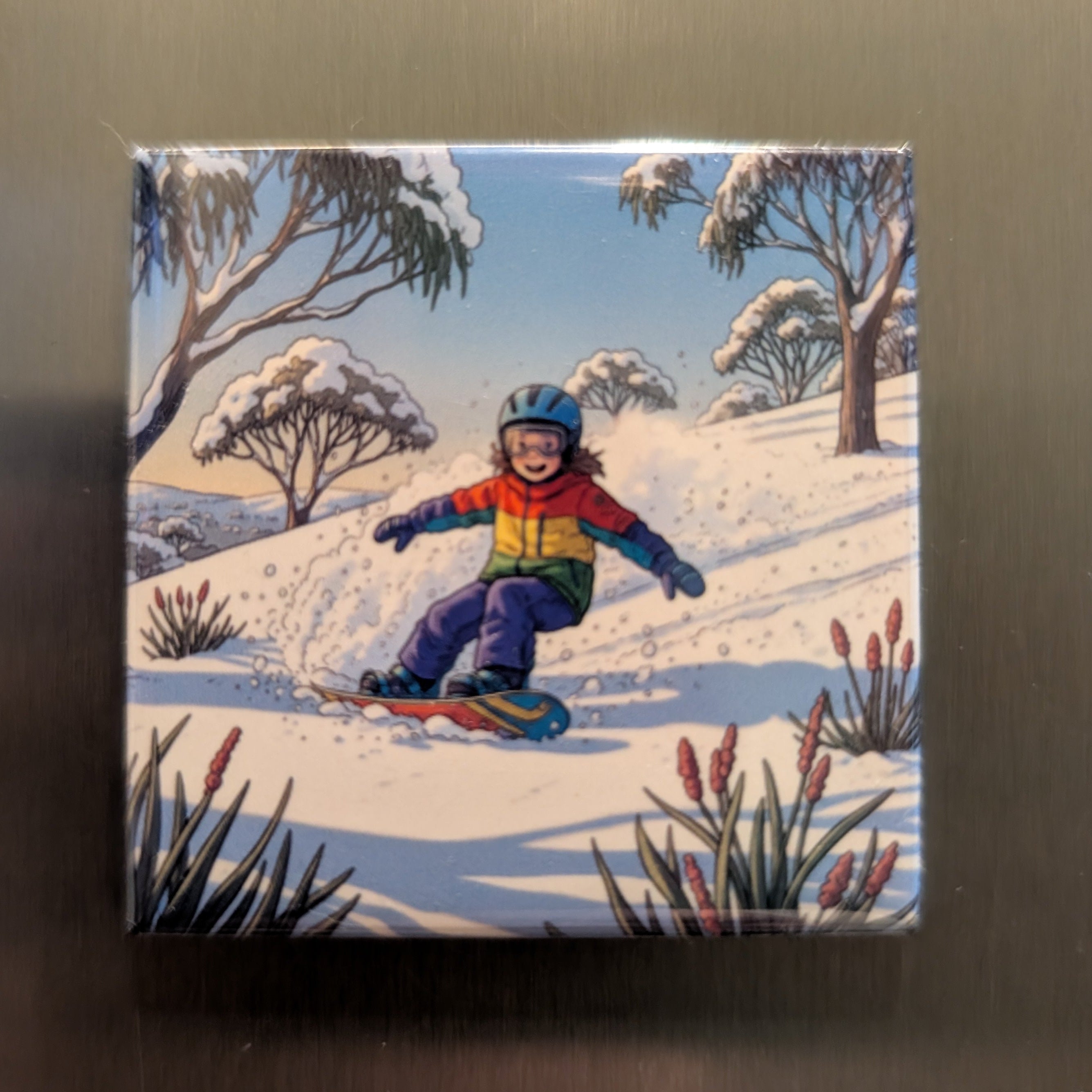 Fridge magnet with a colorful illustration of a child snowboarding in a snowy landscape.