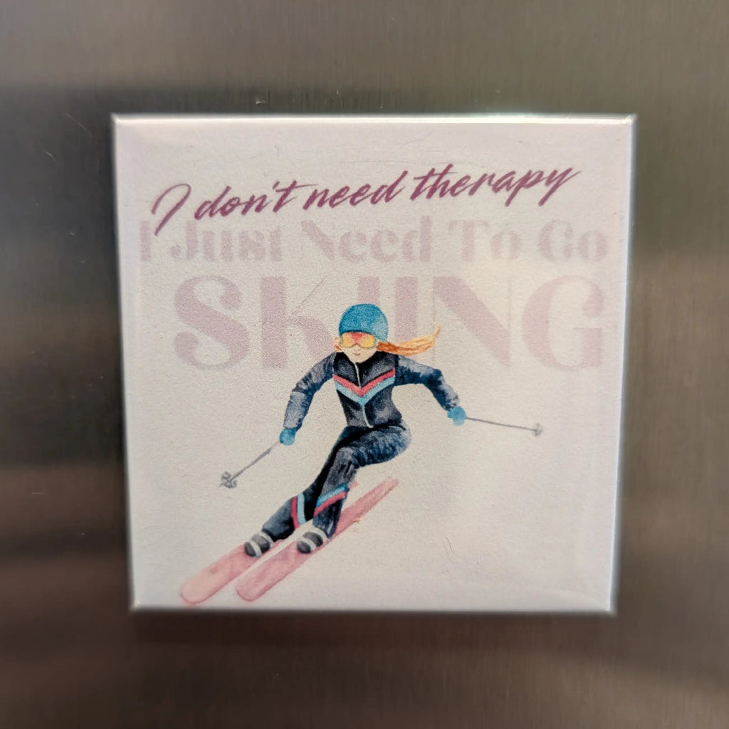 Fridge magnet with a skier illustration and text on a metallic surface