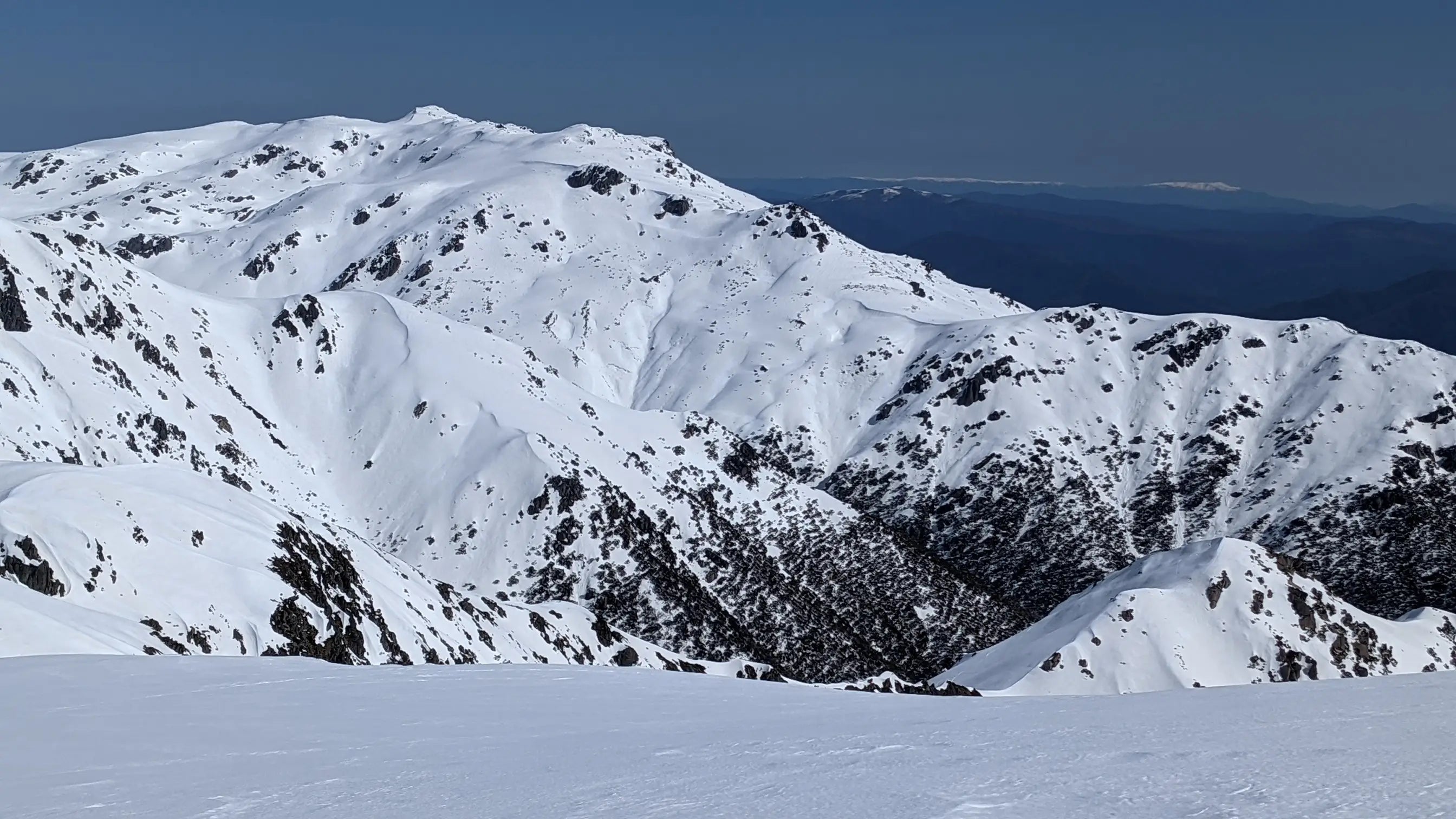 Snow-covered mountain range with a clear blue sky